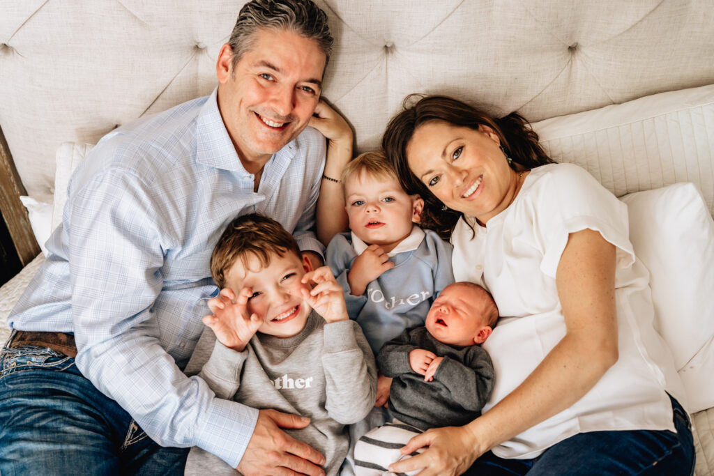 family smiling with newborn and two older children