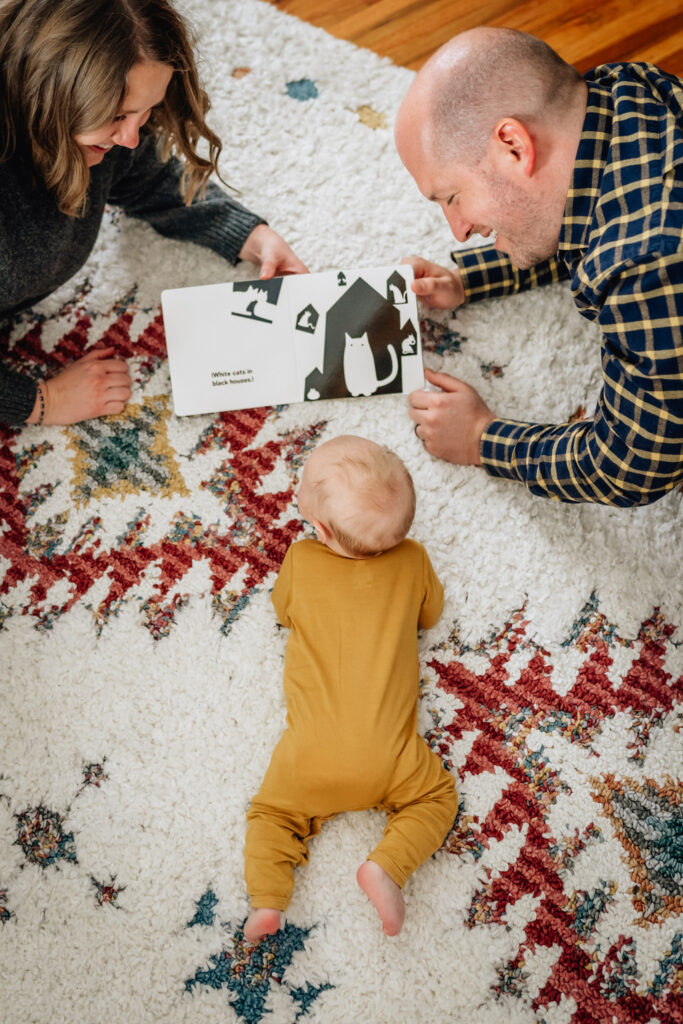 3 month baby lying on rug with parents looking at book