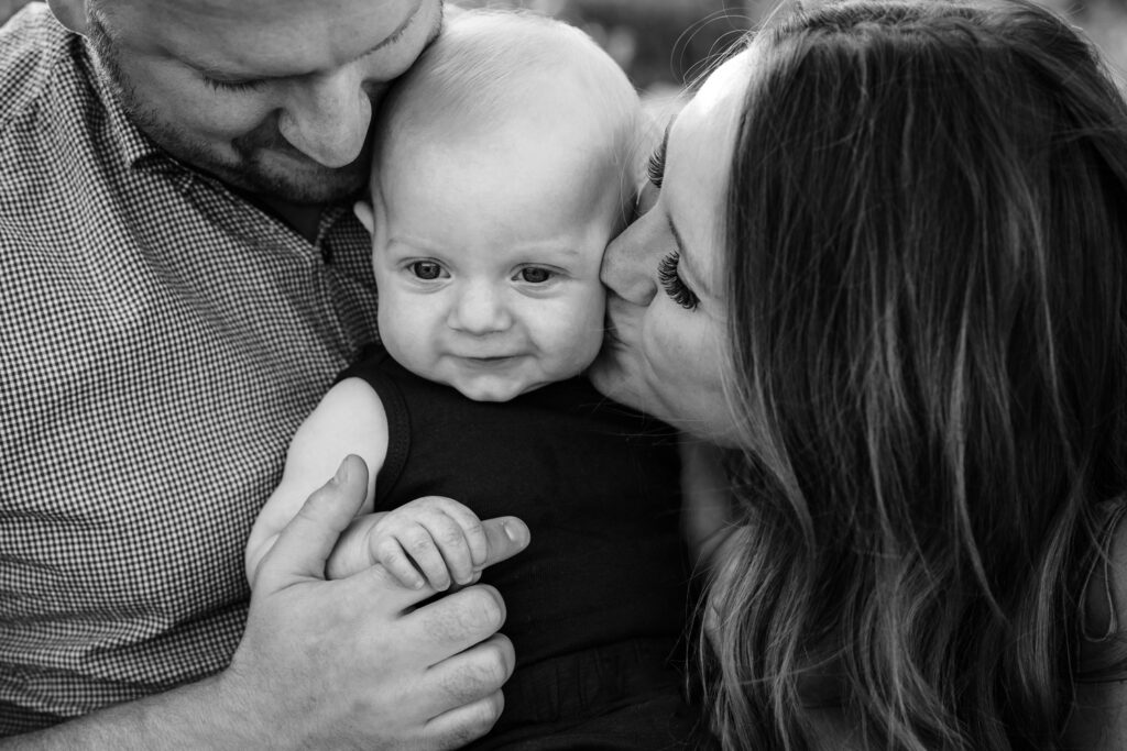 6 month baby kissed bu mother in fathers arms