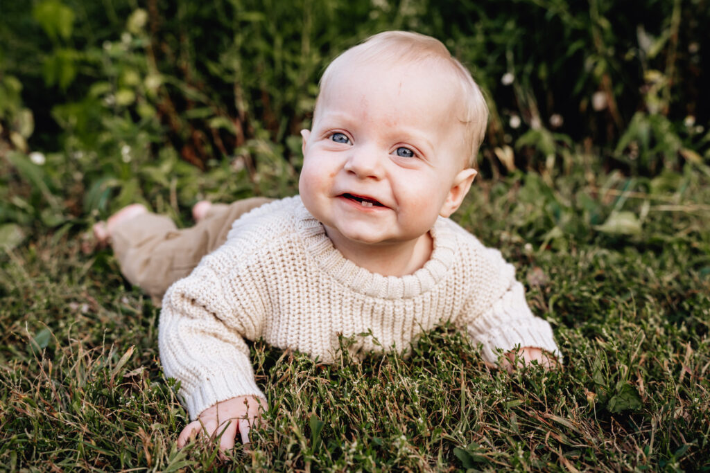 Smiling 9 month baby lying in grass