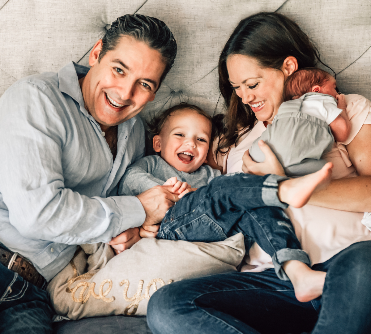 family of four on a bed with mother, father, son, and infant daughter