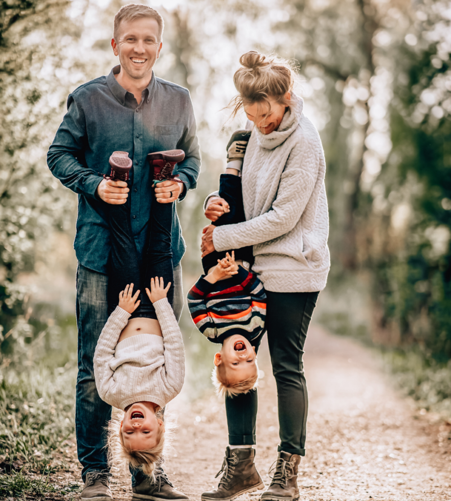 father, mother, daughter, and son, father and mother are holding their children upside down, making them laugh for the photo 