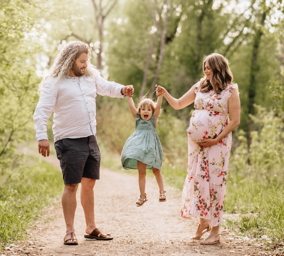 family of three on outdoor trail on a road with mother, father, and daughter