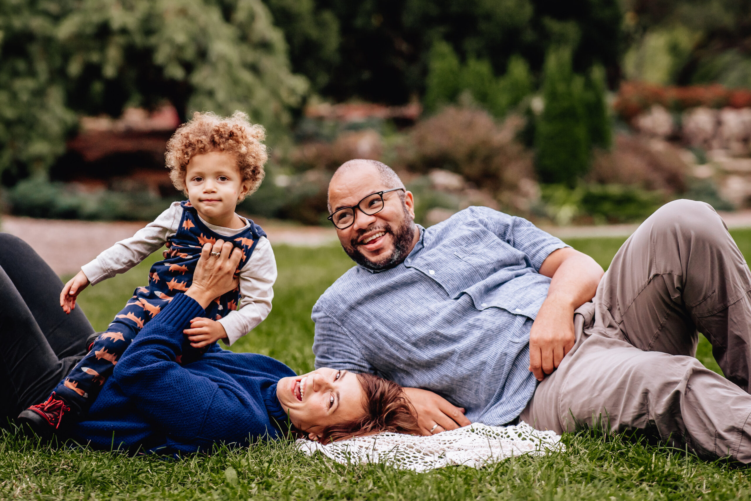 mother, father, and son laying on the grass laughing together