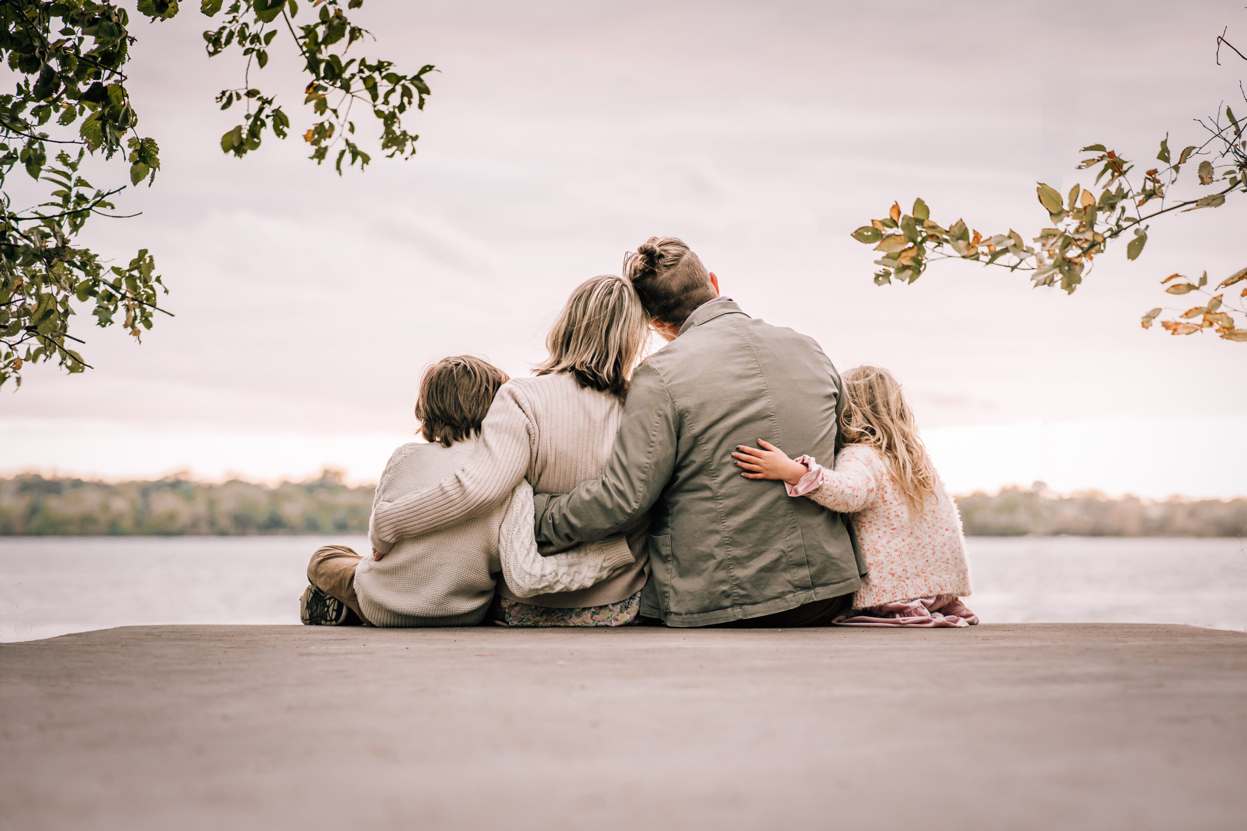 family of four sitting together and looking at a lake together