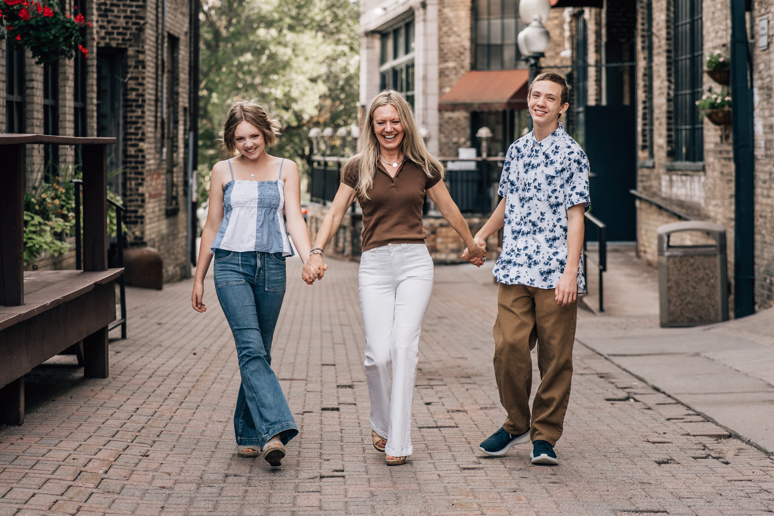 three siblings walking on a street - two sisters and a brother walking and holding hands