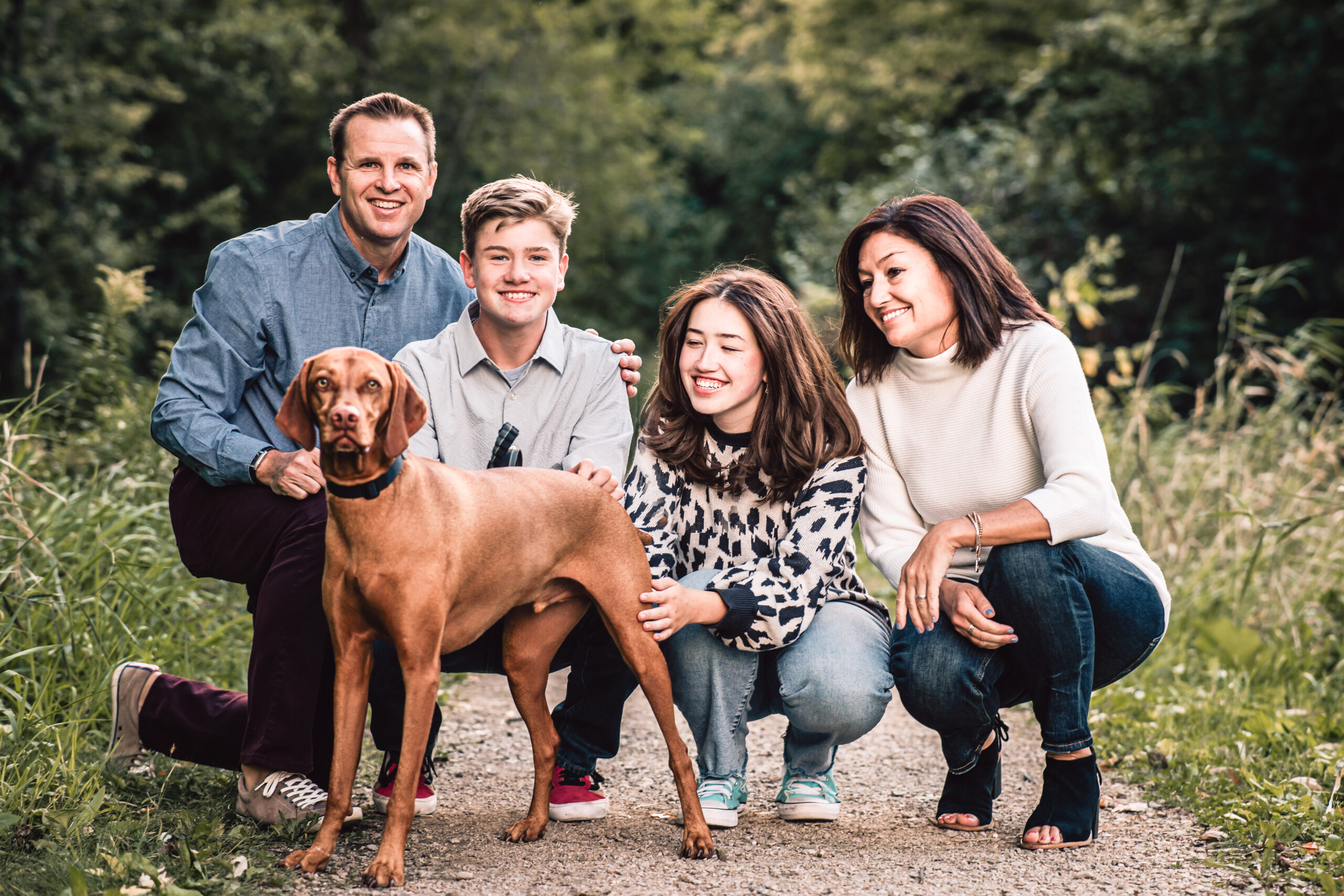 family posing for a picture with their dog. family consists of mother, father, and a daughter and son. 