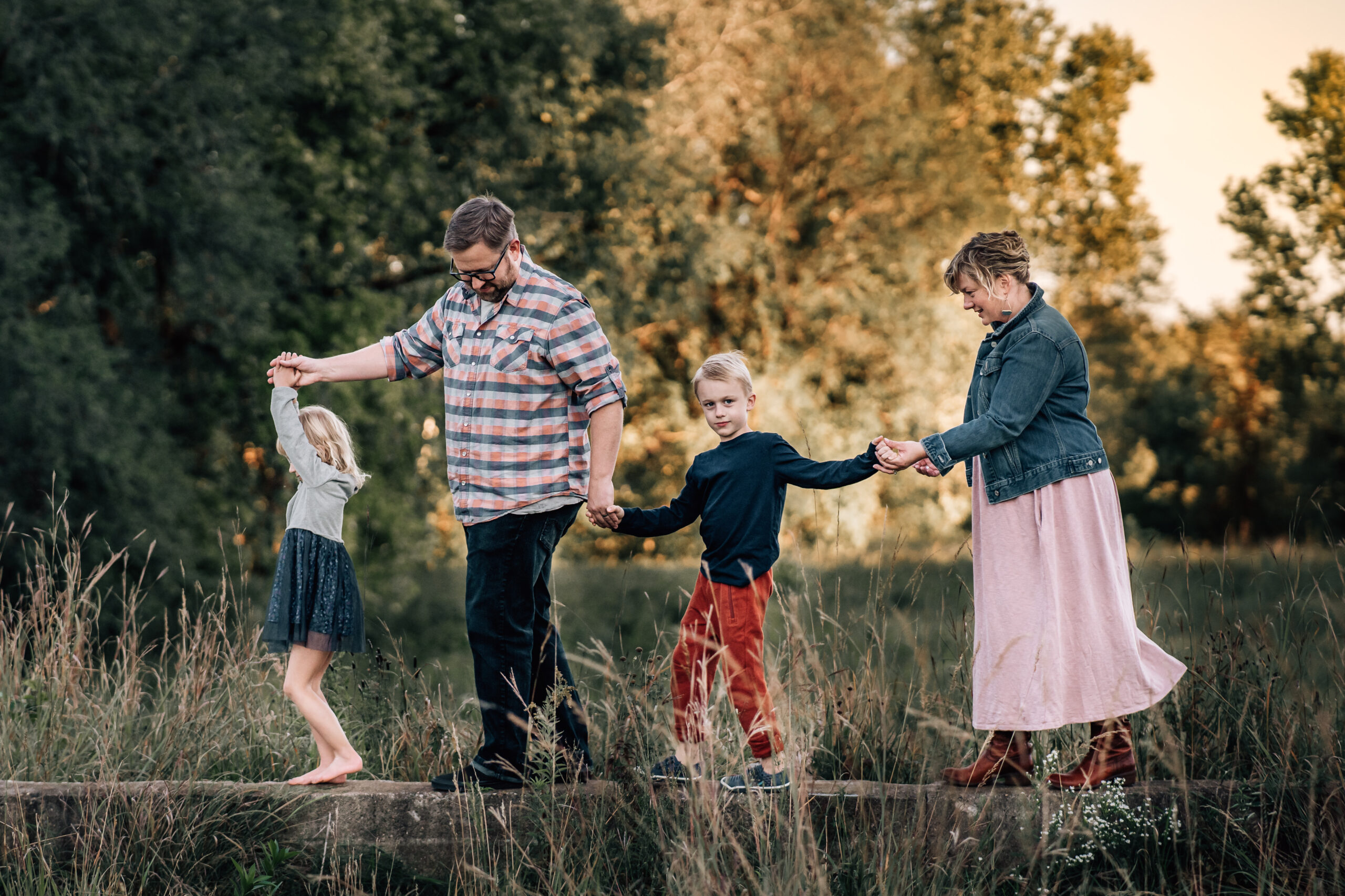 mother, father, and two young children walking through the water together holding hands 