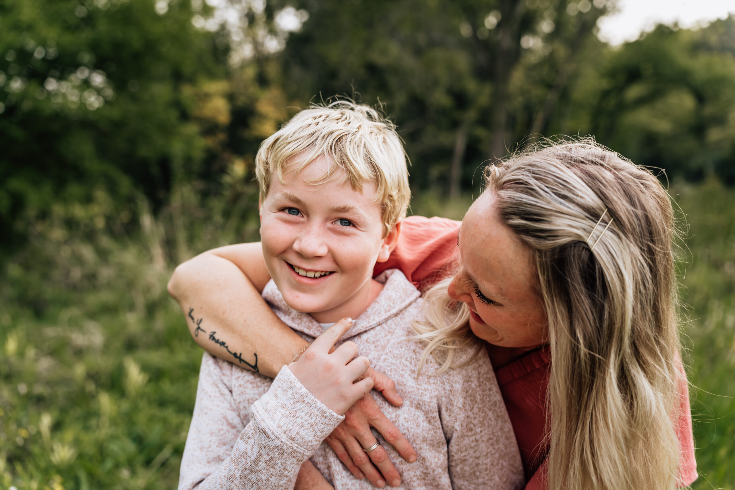 mother looking down at her young son with her arm wrapped around his shoulder. 