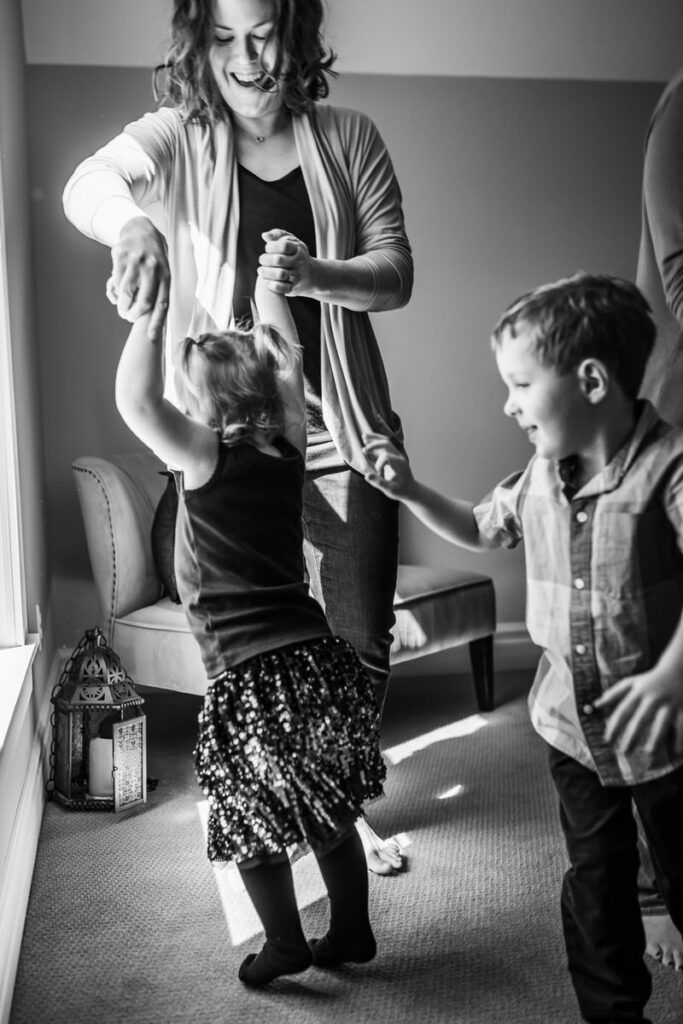 a mother dancing with her young daughter while her son looks on