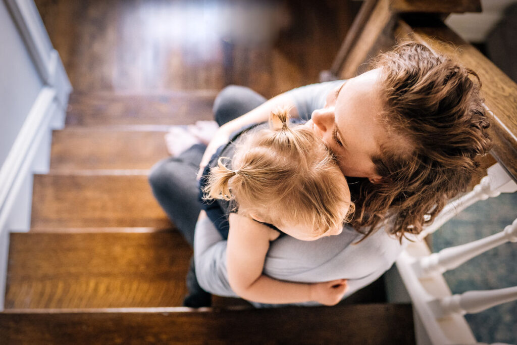 a mother sitting on stairs hugging a small child