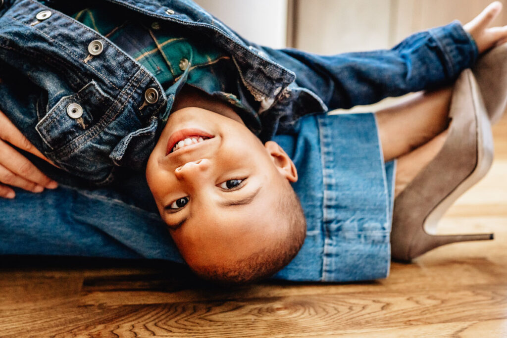 a child smiling upside down while lying on an adult's lap