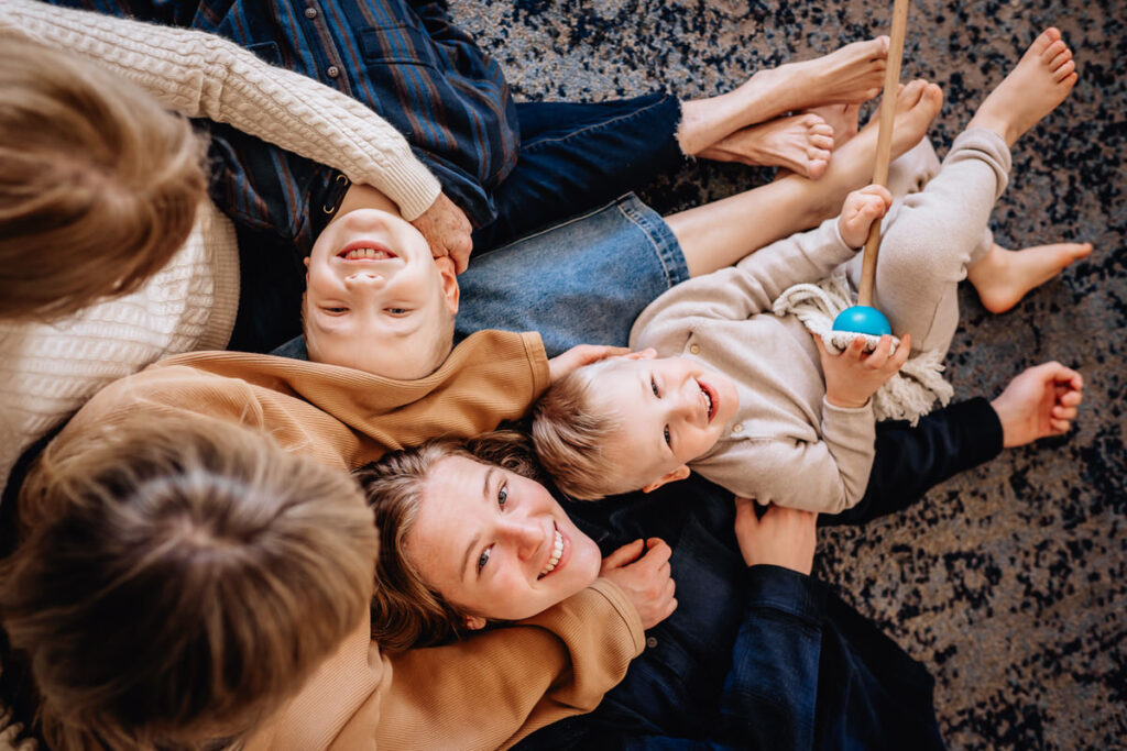 a family lying on the floor together, smiling and embracing each other