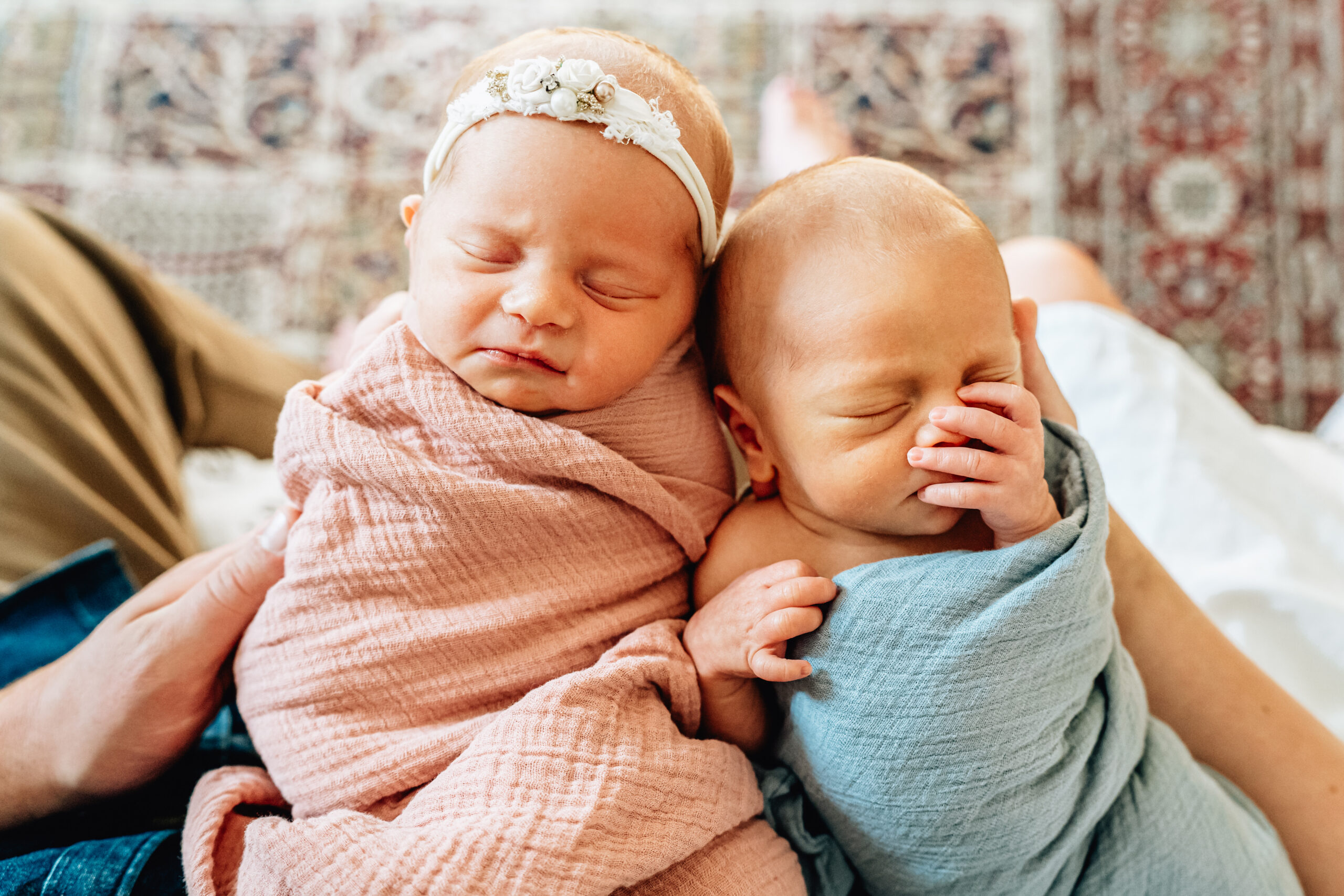 Two newborn babies - a baby boy and a baby girl swaddled in blue and pink cloths. 