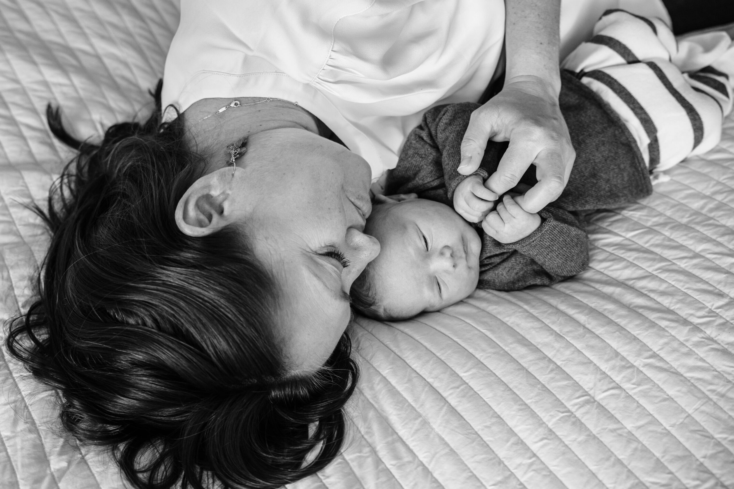 Mother and newborn laying on a bed together.