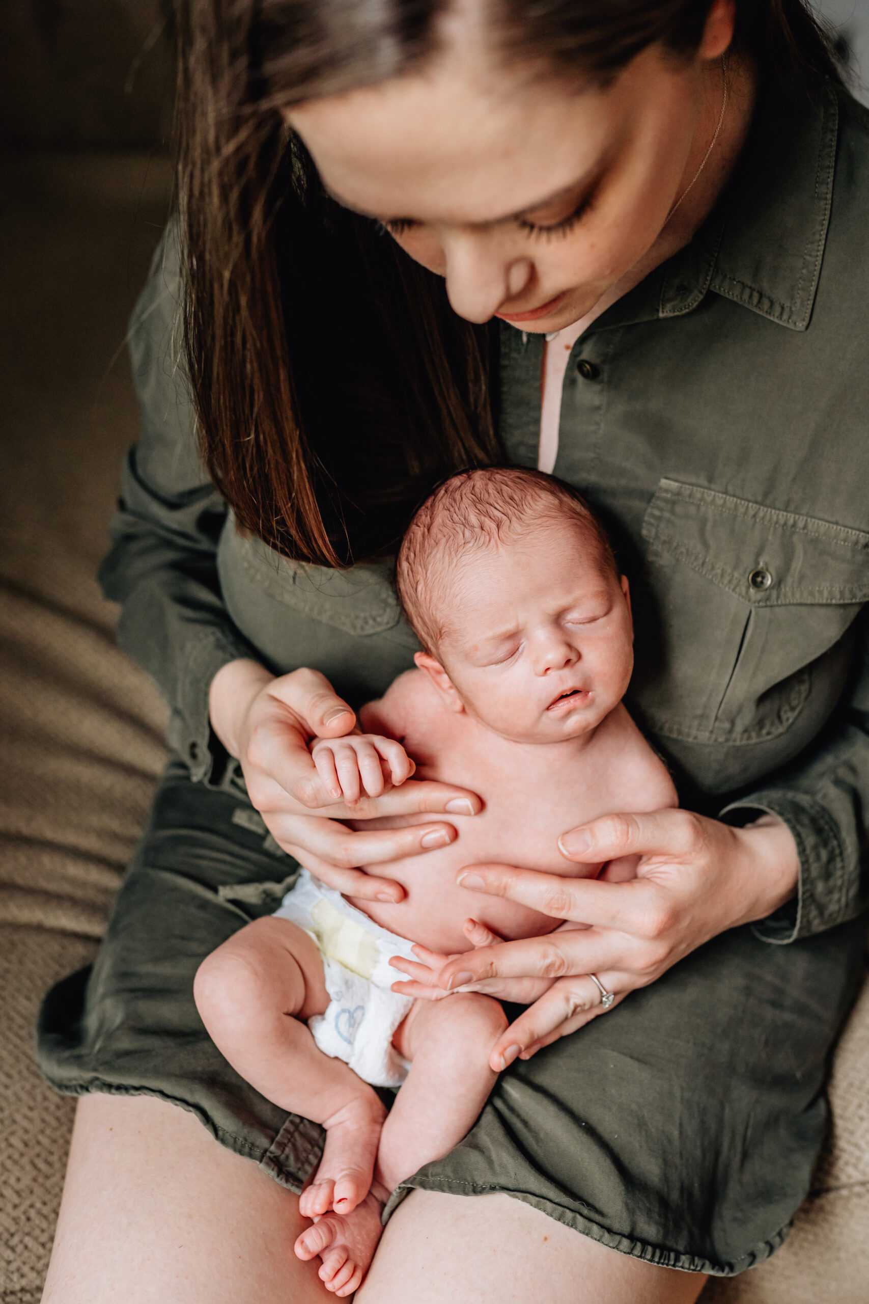 Mother looking down and holding her newborn.